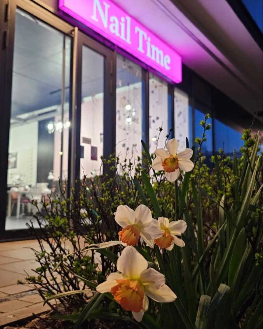 Wieczorny widok salonu Nail Lash Time z kwiatami przed wejściem